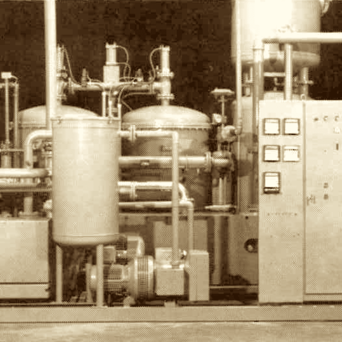 Vintage sepia photo of an early MAHLER gas plant skid with two cylindrical vessels, connected piping and valves, a small pump unit, and a tall electrical control cabinet.