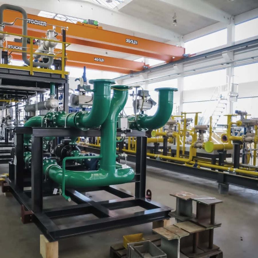 MAHLER-Anlagen-Skid in der Fertigungshalle mit großen grünen Prozessrohrleitungen und gelben Ventilblöcken unter Brückenkränen.