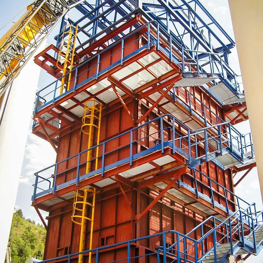 Tall steel plant tower with multi-level platforms, stairs, and ladders under construction.